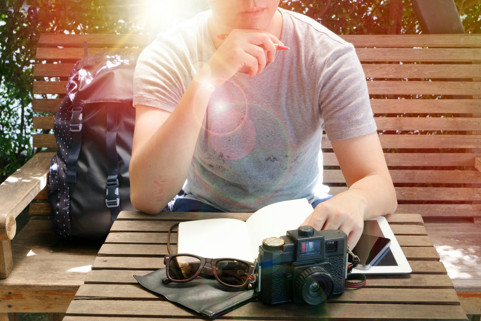 Podróżując po Chinach z plecakiem i notatnikiem: jak codzienne zapiski stały się moją kroniką przygód Podróżnik z aparatem i notatnikiem siedzi na ławce w słońcu