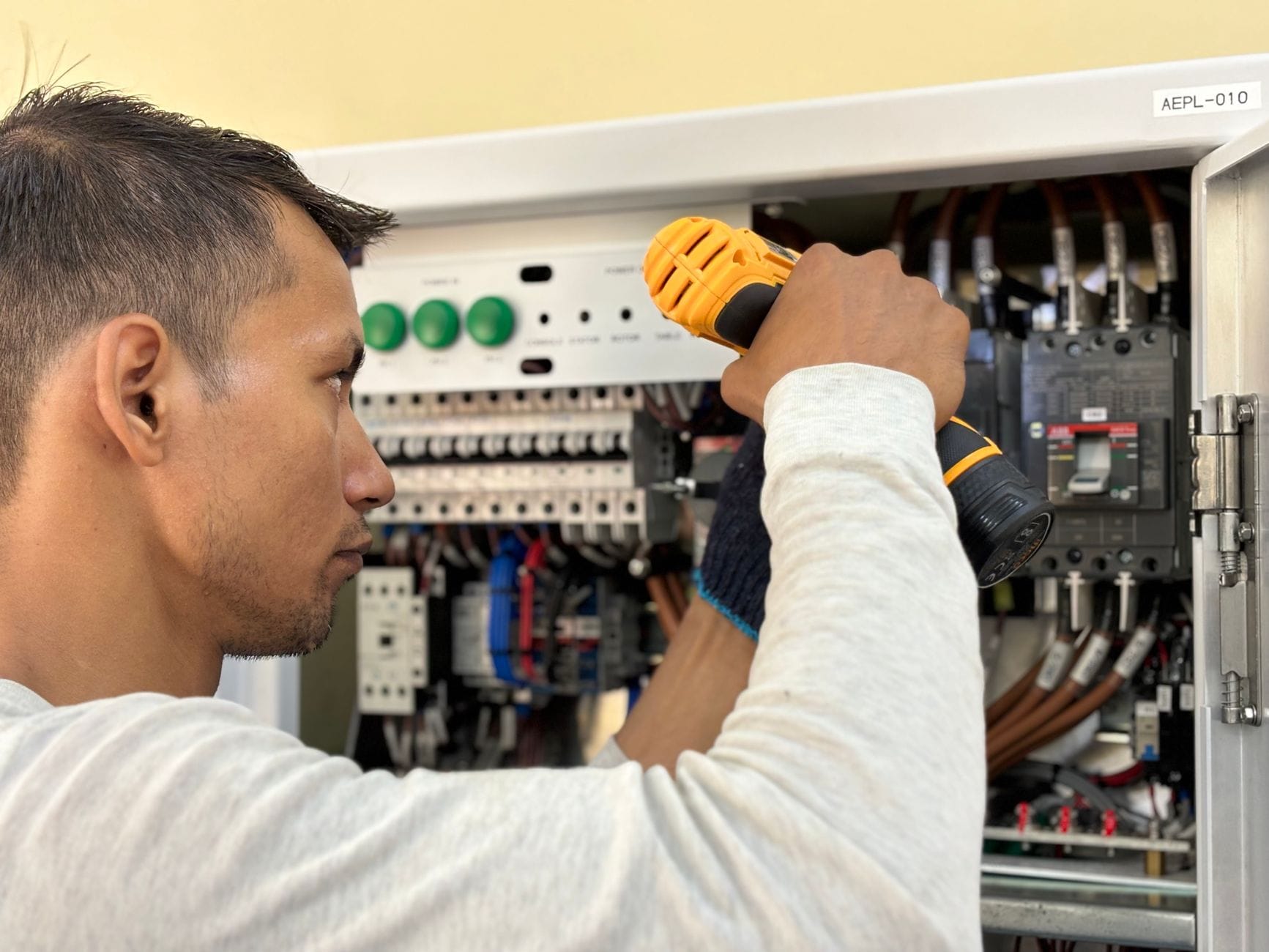 Elektryk wierci w rozdzielnicy z wyłącznikami w instalacji domowej
