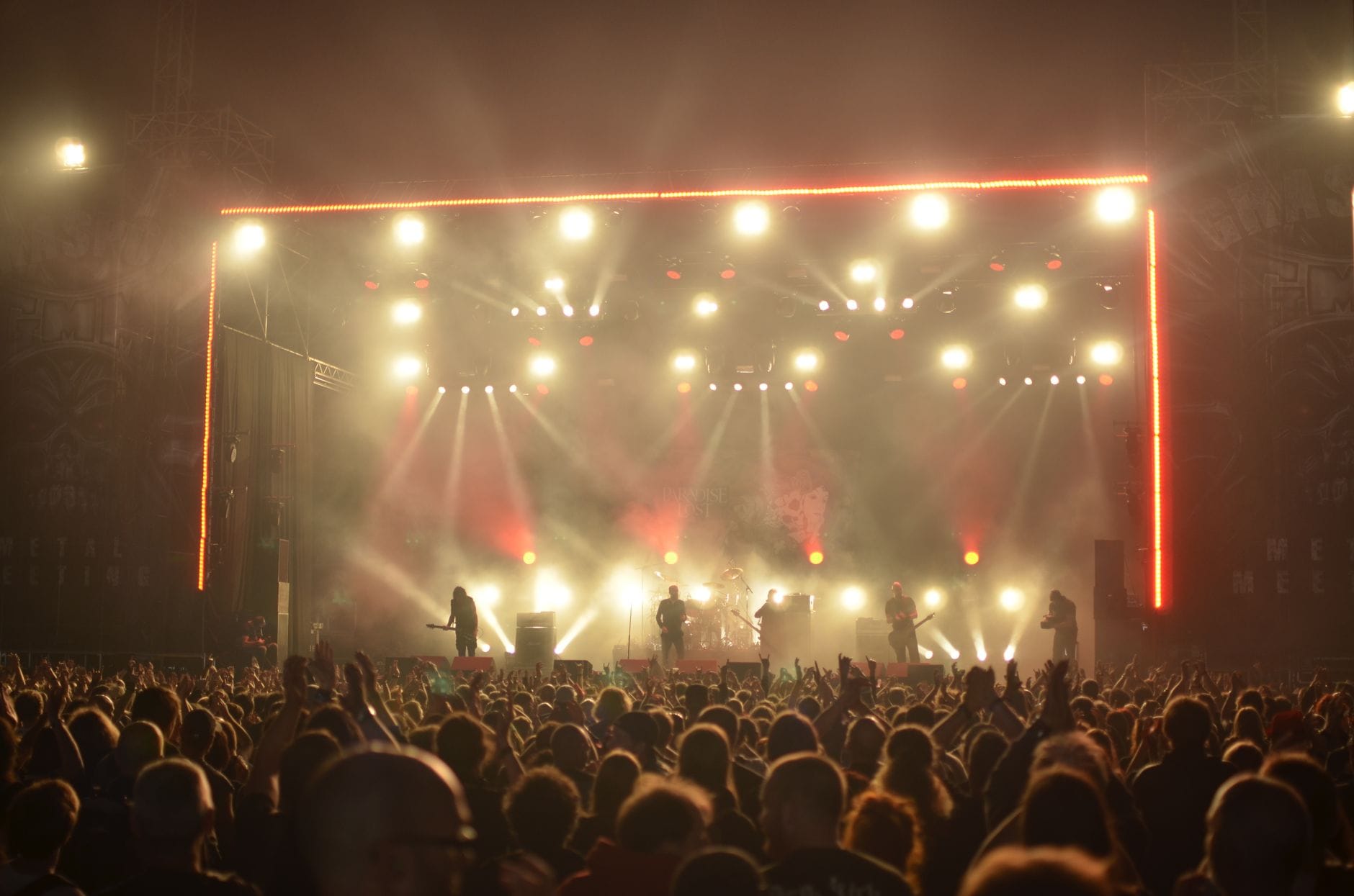 Nocny rockowy koncert plenerowy z zespołem na scenie i tłumem fanów